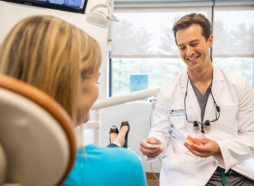Dentist smiling while showing clear aligners to a patient