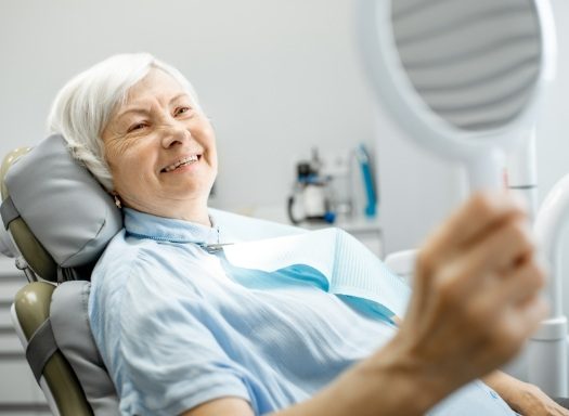 Senior dental patient seeing her smile in mirror