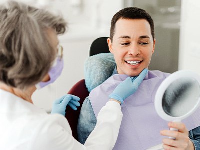 Man smiling at reflection in mirror with dentist